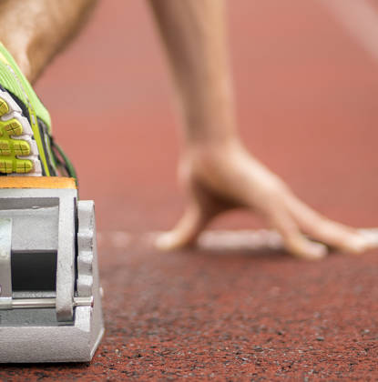 Close-up van hand en voet in startblok