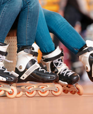 Inline skating. Closeup of two beautiful teen girls showing their rollerblades