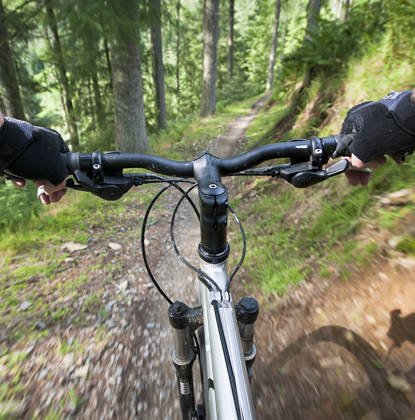 Motion blur as a mountain biker speeds down a woodland trail, photographed on the moving bike.