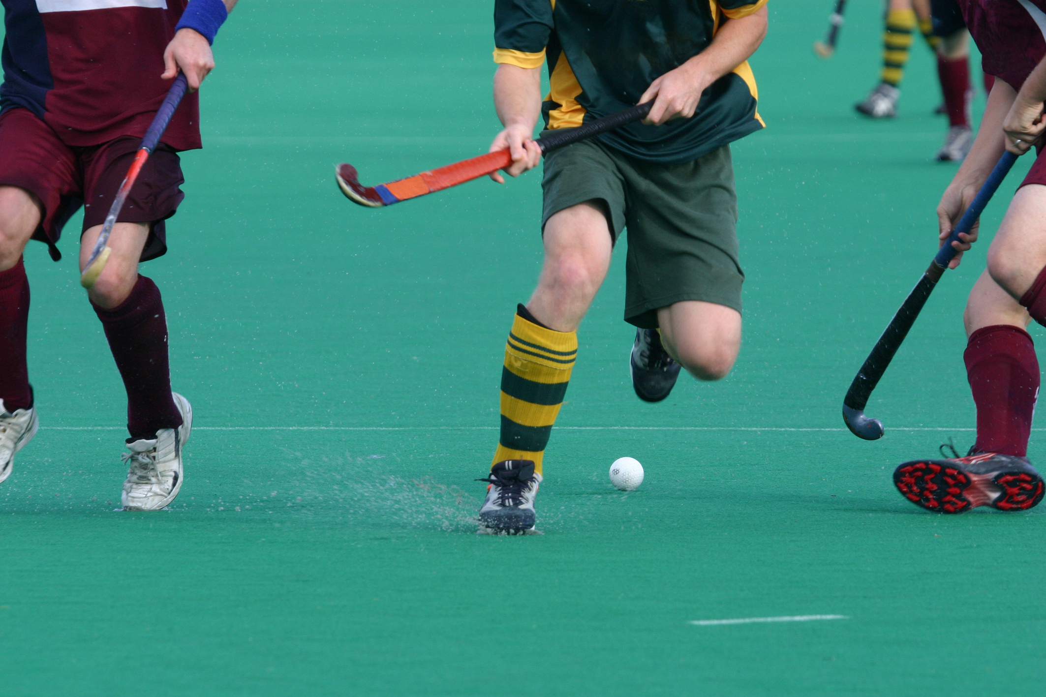Drie hockeyspelers vechten om bal met stick