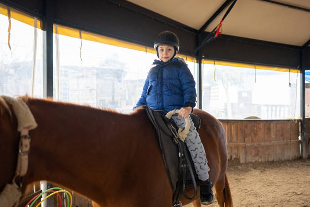 Little boy riding training horse