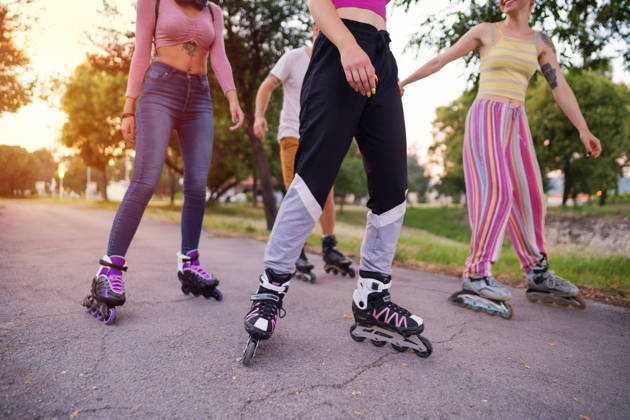 Low-angle view of a small group of unrecognizable Caucasian people rollerblading on a sunny day.
