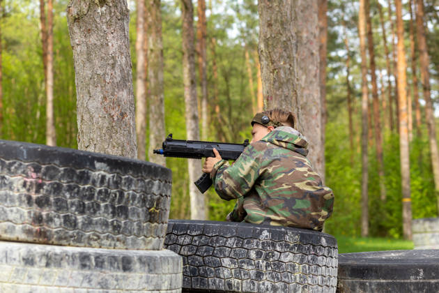 Boy weared in camouflage playing laser tag in special forest playground. Laser Tag is a command military tactical game using safe laser weapons and sensors that record hits.