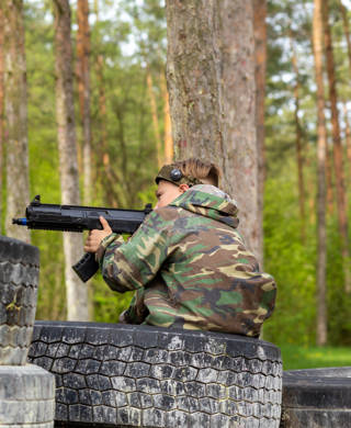 Boy weared in camouflage playing laser tag in special forest playground. Laser Tag is a command military tactical game using safe laser weapons and sensors that record hits.