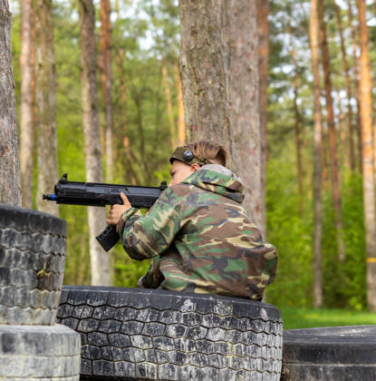 Boy weared in camouflage playing laser tag in special forest playground. Laser Tag is a command military tactical game using safe laser weapons and sensors that record hits.