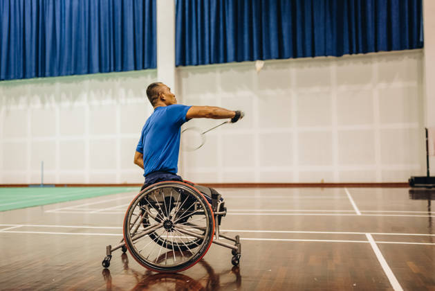 Man in rolstoel slaat met badmintonracket