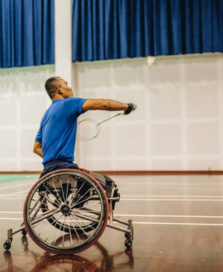 Man in rolstoel slaat met badmintonracket