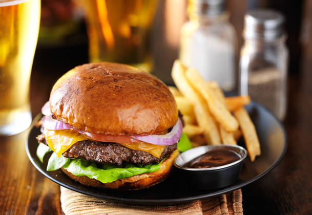 cheeseburger and fries on plate served with beer at restaurant