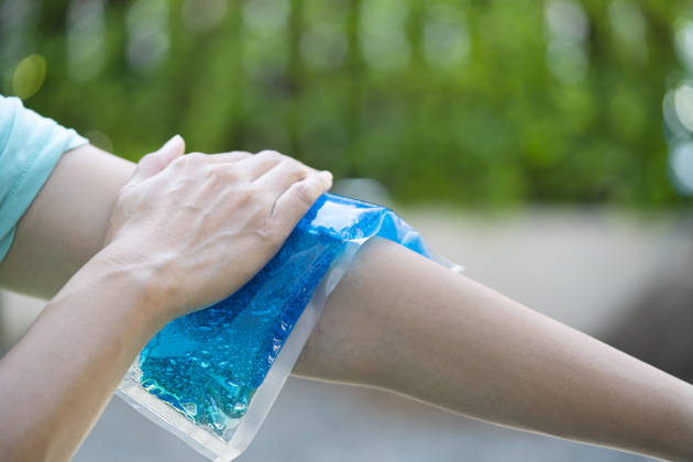 woman putting an ice pack on her arm pain, healthy and medical concept