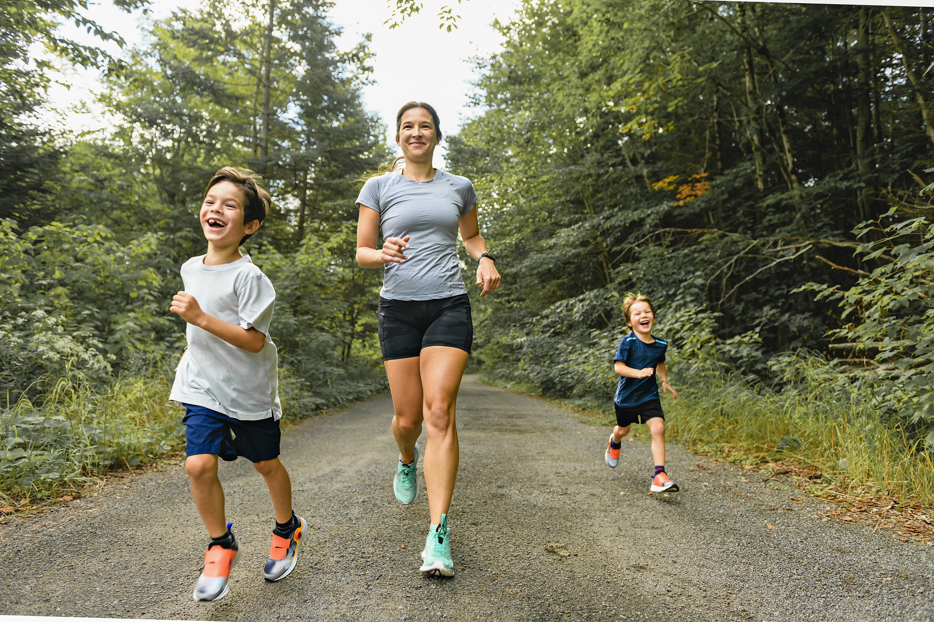 A mother and sons running outside in forest