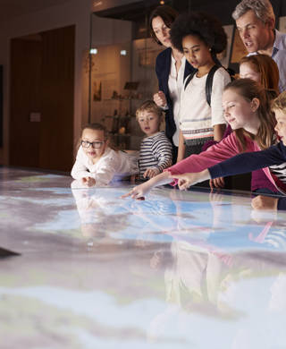 Pupils On School Field Trip To Museum Looking At Map
