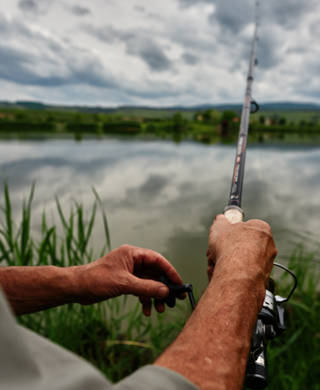 unrecognizable fishing man at the edge of lake enjoying retirement activities.