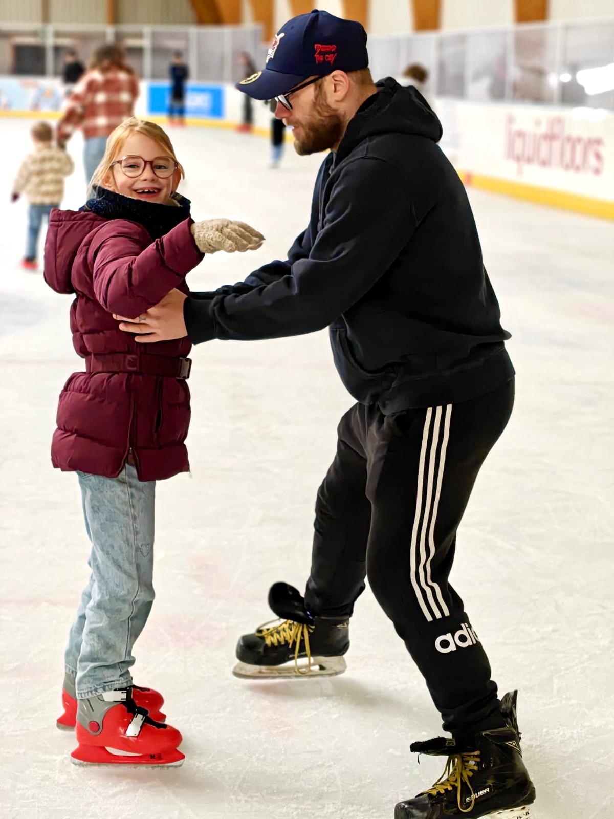 Jong meisje op schaatsen wordt begeleid op het ijs door trainer of coach