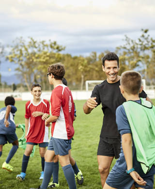 Lachende trainer en tieners op voetbalveld