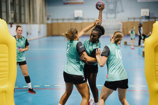 Handbalspeelster probeert bal te gooien terwijl tegenspeelsters dat verhinderen