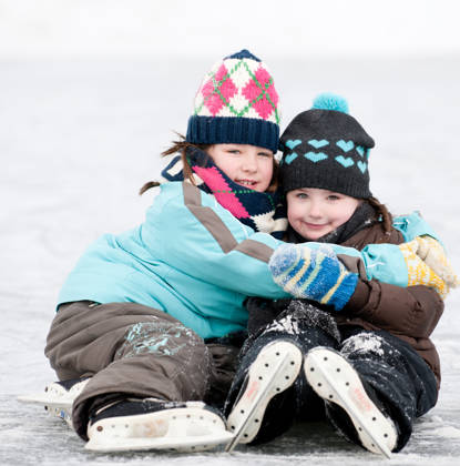 Little girls ice skating outside on a pond