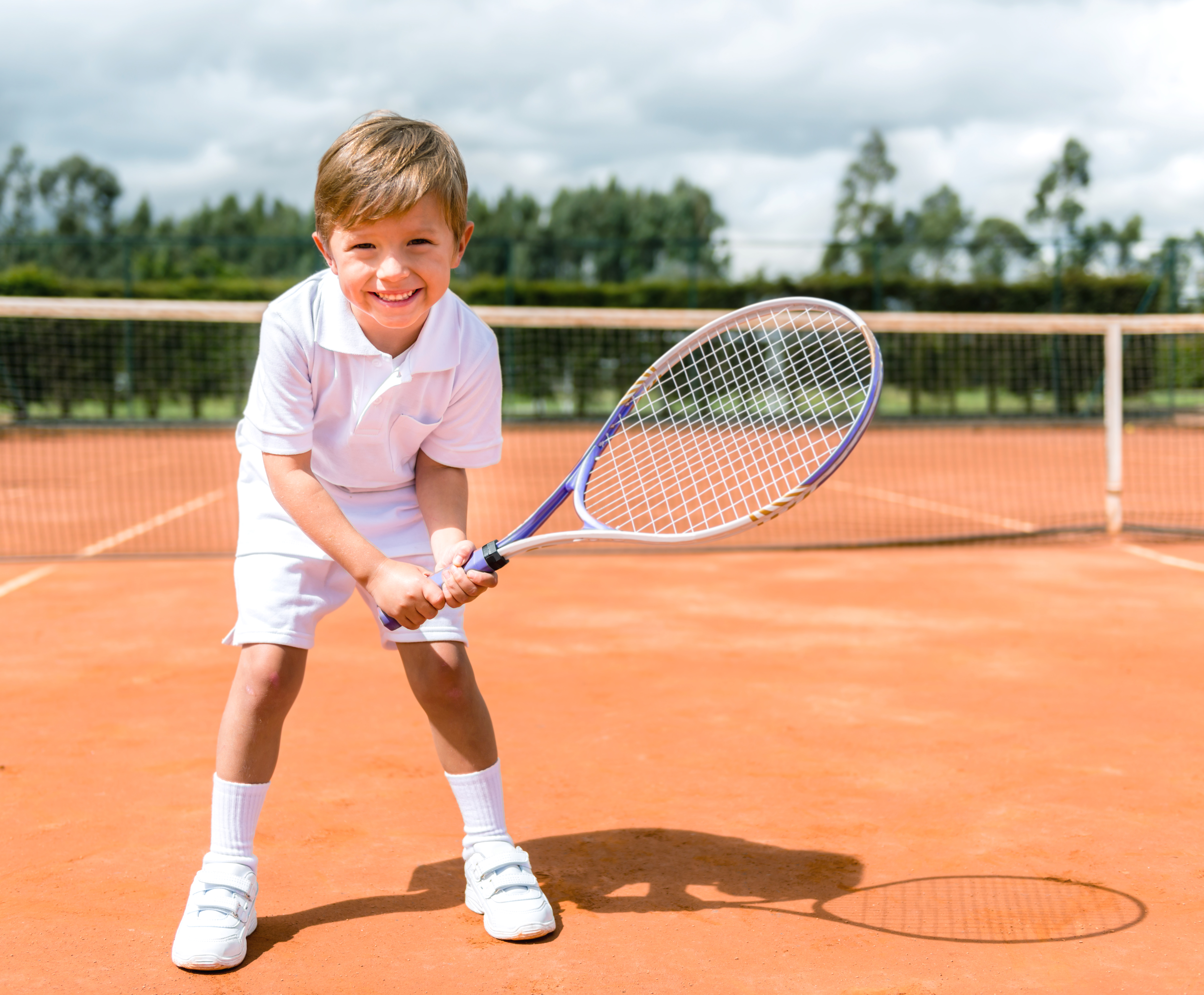 Jongen op gravel tennisveld