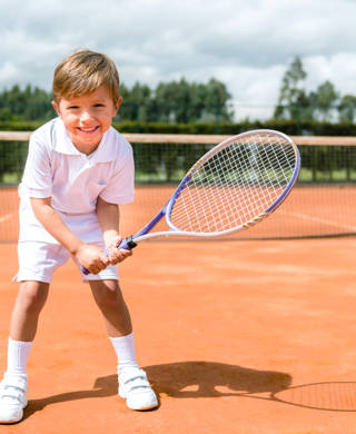 Jongen op gravel tennisveld