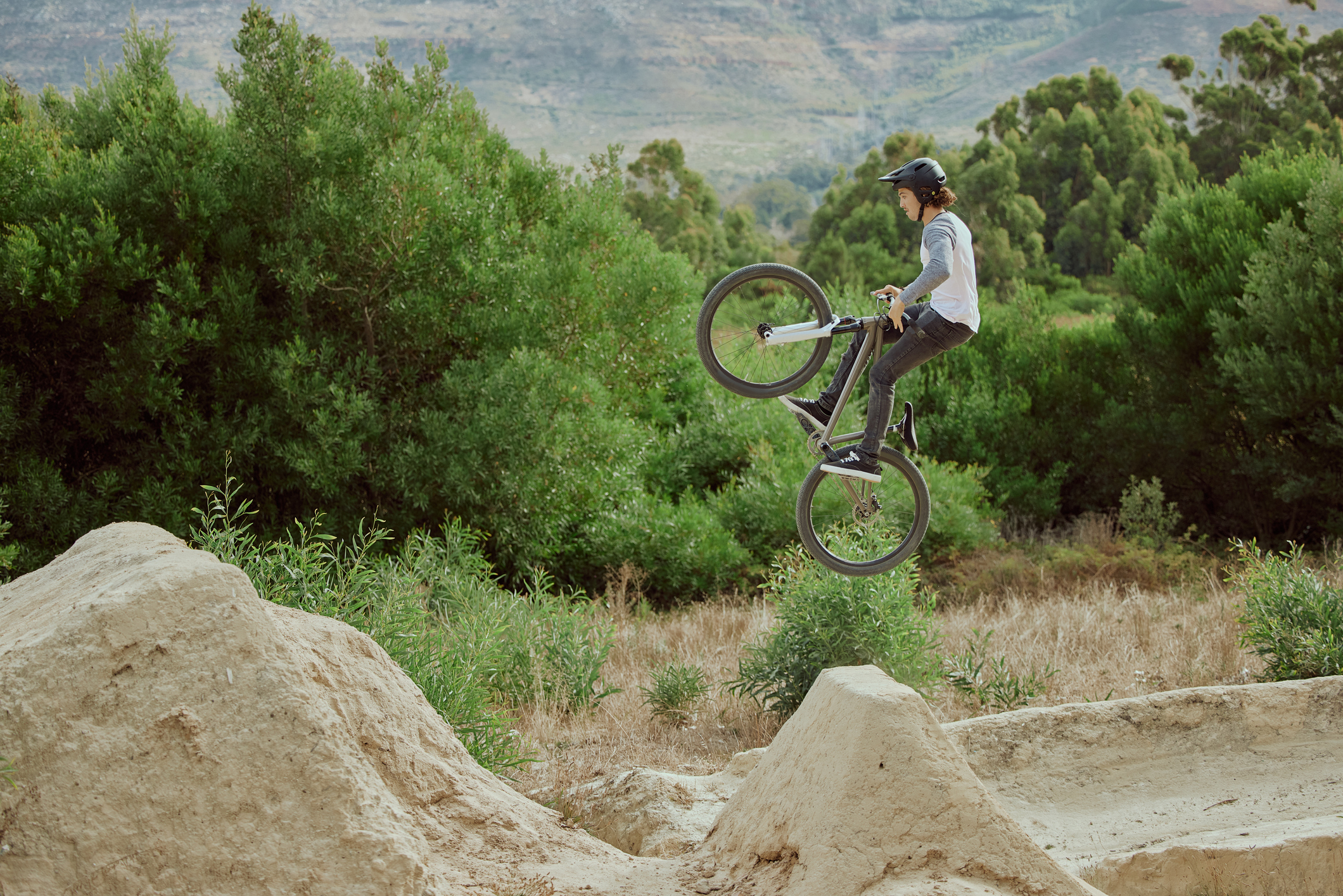 Cycling jump, sports or mountain bike man with air trick for fun, exercise or training for speed travel race. Dirt ramp, bicycle nature flight or extreme athlete with freestyle action