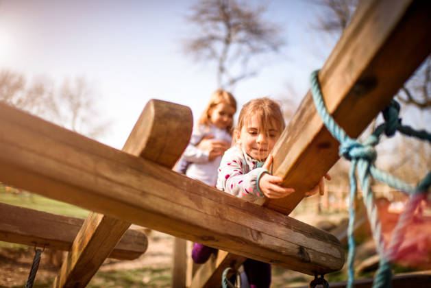 Little girls playing in the park on wooden planks.