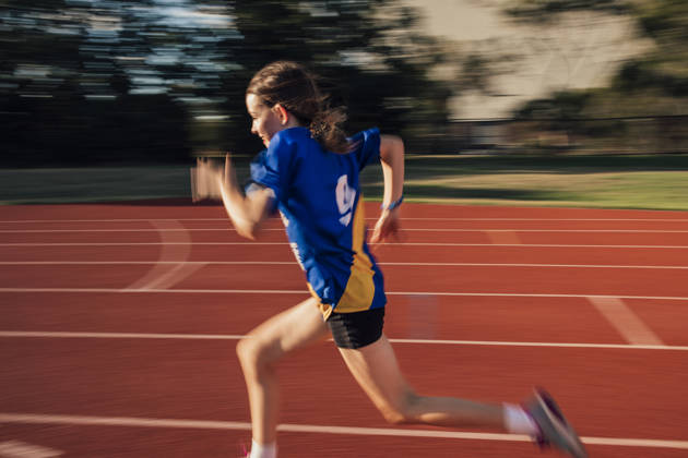 Little girl is doing speed training on the running track at athletics club.