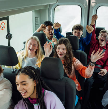 A high angle view of group of young teenage students enjoying the bus ride to a school field trip to Rothbury in Northumberland in the North East of England. They are singing and playing games to pass the time as they travel.