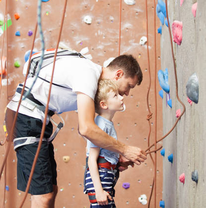 Kleuter met coach op klimmuur