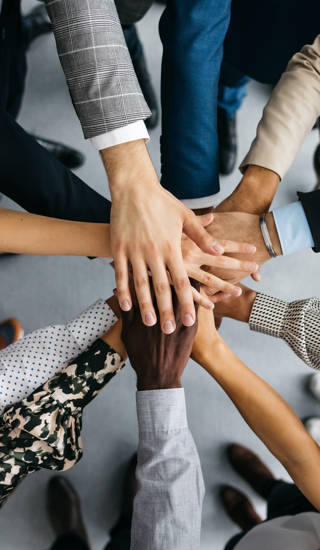 Verschillende handen op elkaar van multiculturele groep mensen