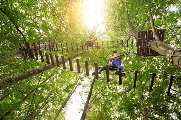 low angle view of three friends in adventure park climbing on suspension bridge.summer day.