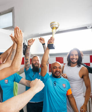 Group of male soccer players raising a trophy after winning the final match of the competition.