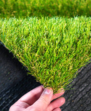 Hand houdt stukje kunstgras vast