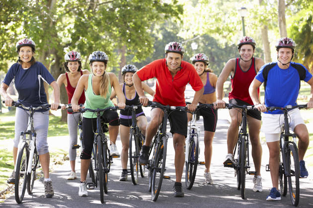 Group Of Cyclists On Cycle Ride Through Park Smiling To Camera