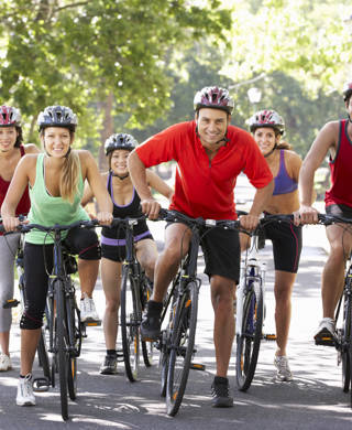 Group Of Cyclists On Cycle Ride Through Park Smiling To Camera