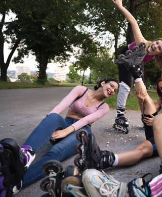 A small group of young Caucasian skaters using a smartphone while taking selfies in the park.