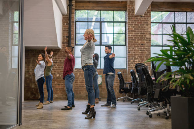 Group of workers exercising at the office while taking an active break - healthy lifestyle concepts