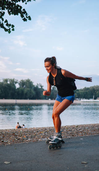 Meisje dat aan het rolschaatsen is op een pad langs het water