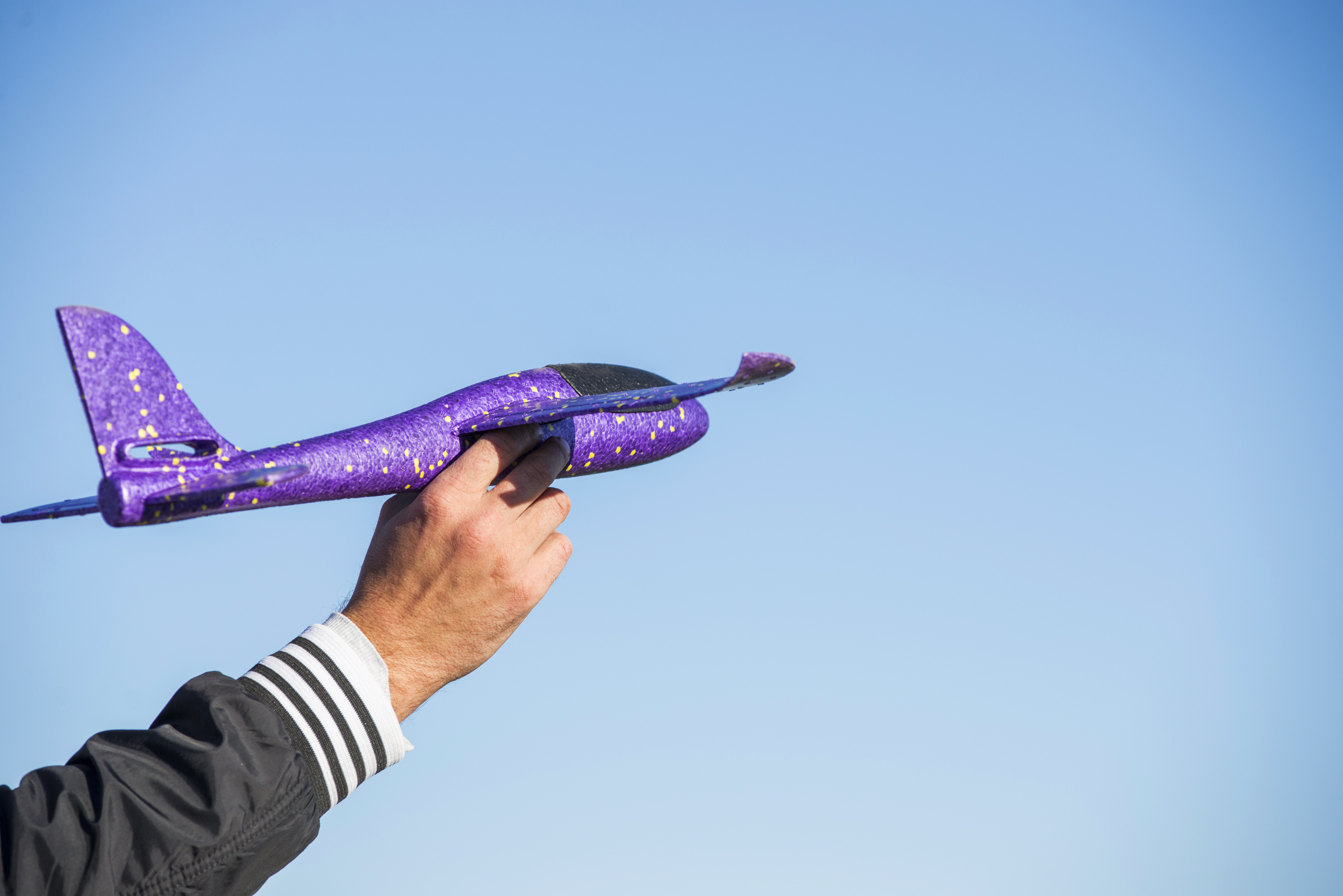 Toy airplane in hand of man and sky background. Toy airplane in the sky