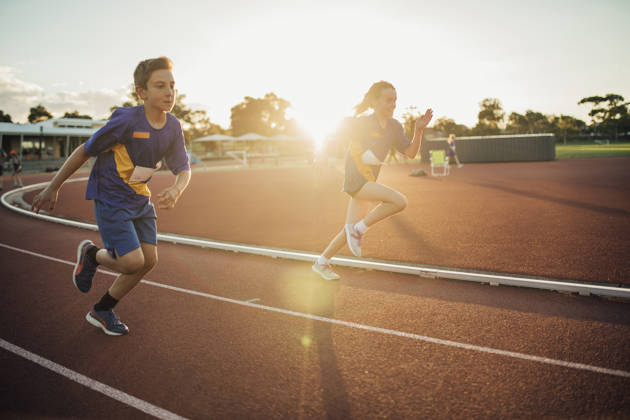 Two girls are racing each other on the running track at athletics club.