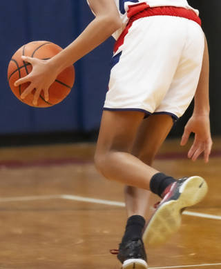 Basketballer dribbelt de bal naar de grond tijdens een wedstrijd