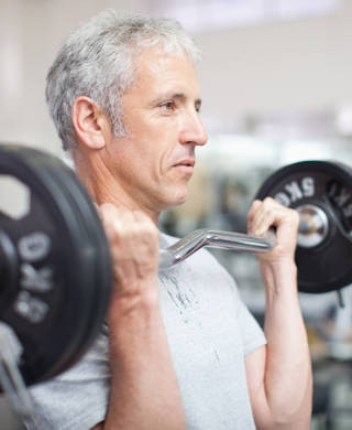 Grijze man heft gewichtsbar tot schouderhoogte