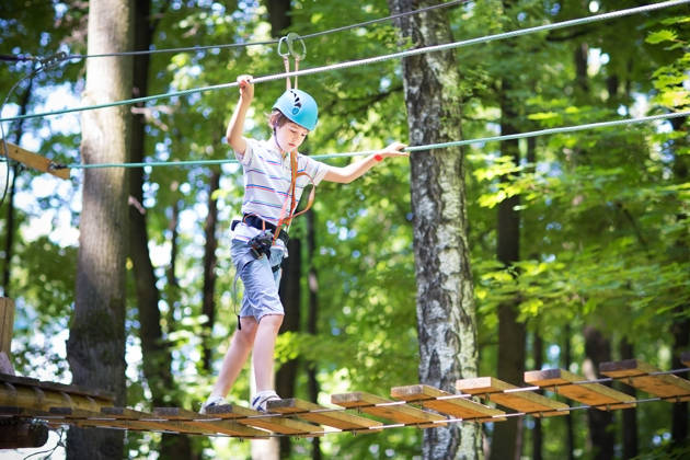 Cute school boy enjoying a sunny day in a climbing activity park