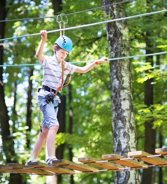 Cute school boy enjoying a sunny day in a climbing activity park