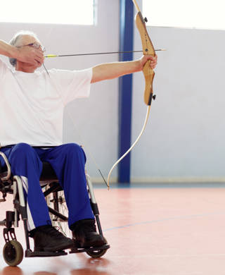 Oudere man in rolstoel met pijl en boog